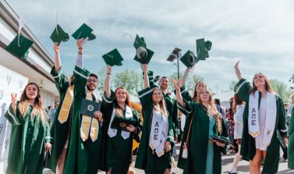 Graduates in robes toss caps at a prior Commencement.