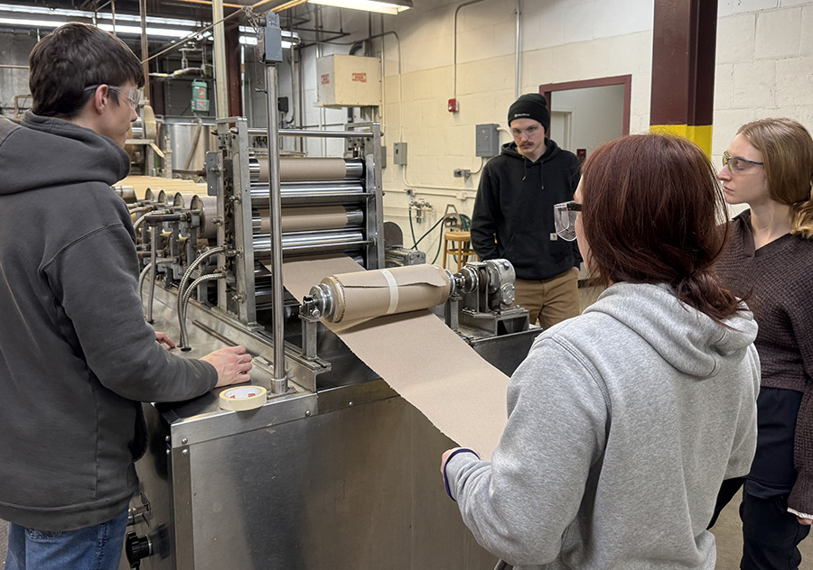 Students inspect paper output in the classroom.