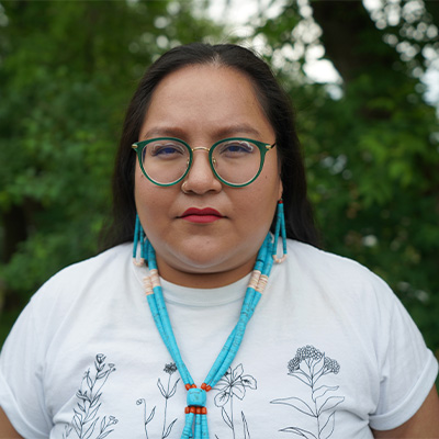 Brenna Yellowthunder wearing a white tshirt, blue beaded necklace and earing