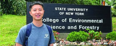 Student standing in front of the SUNY ESF sign on Forestry Drive.