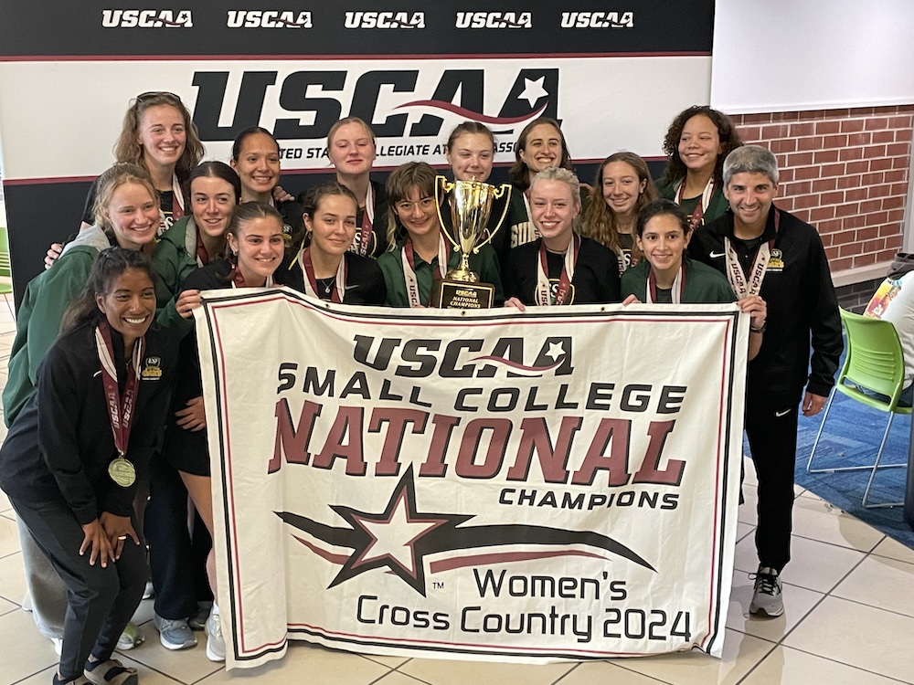 Group of women posing with USCAA small college National Champs banner.