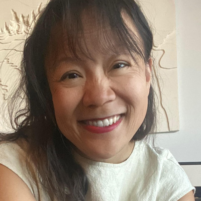 Smiling woman with long dark hair wearing a white shirt.