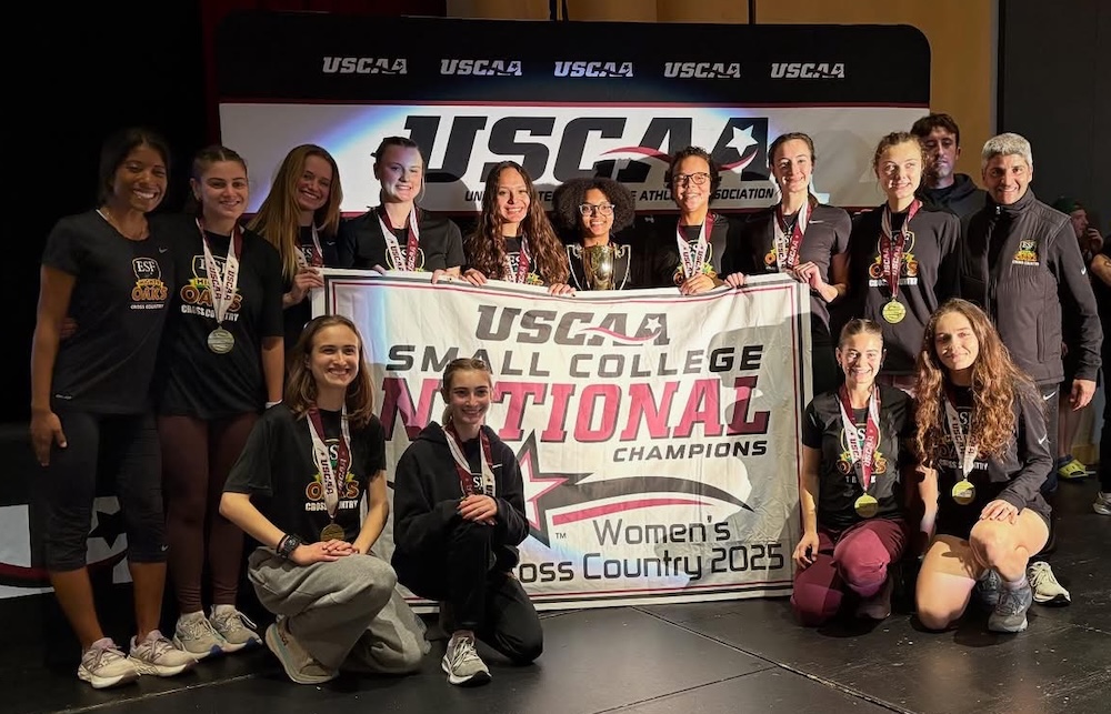 Womens Cross Country team poses with their championship banner.