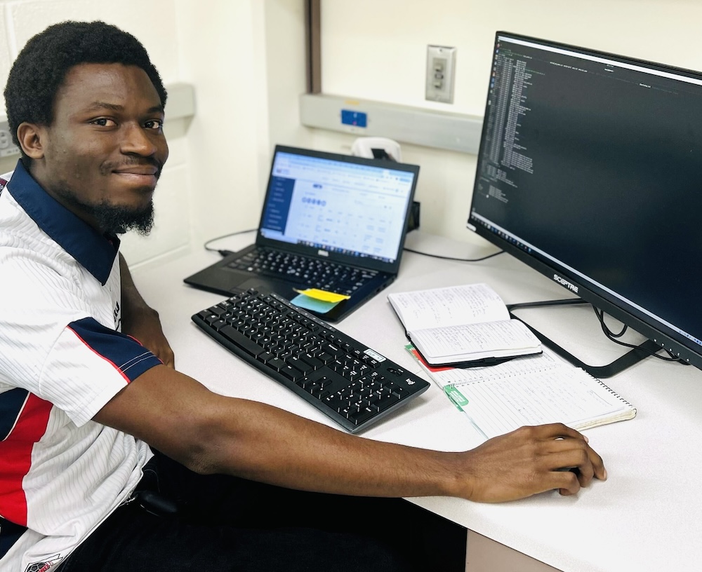 Man with a beard and wearing a white shirt sitting at a computer.