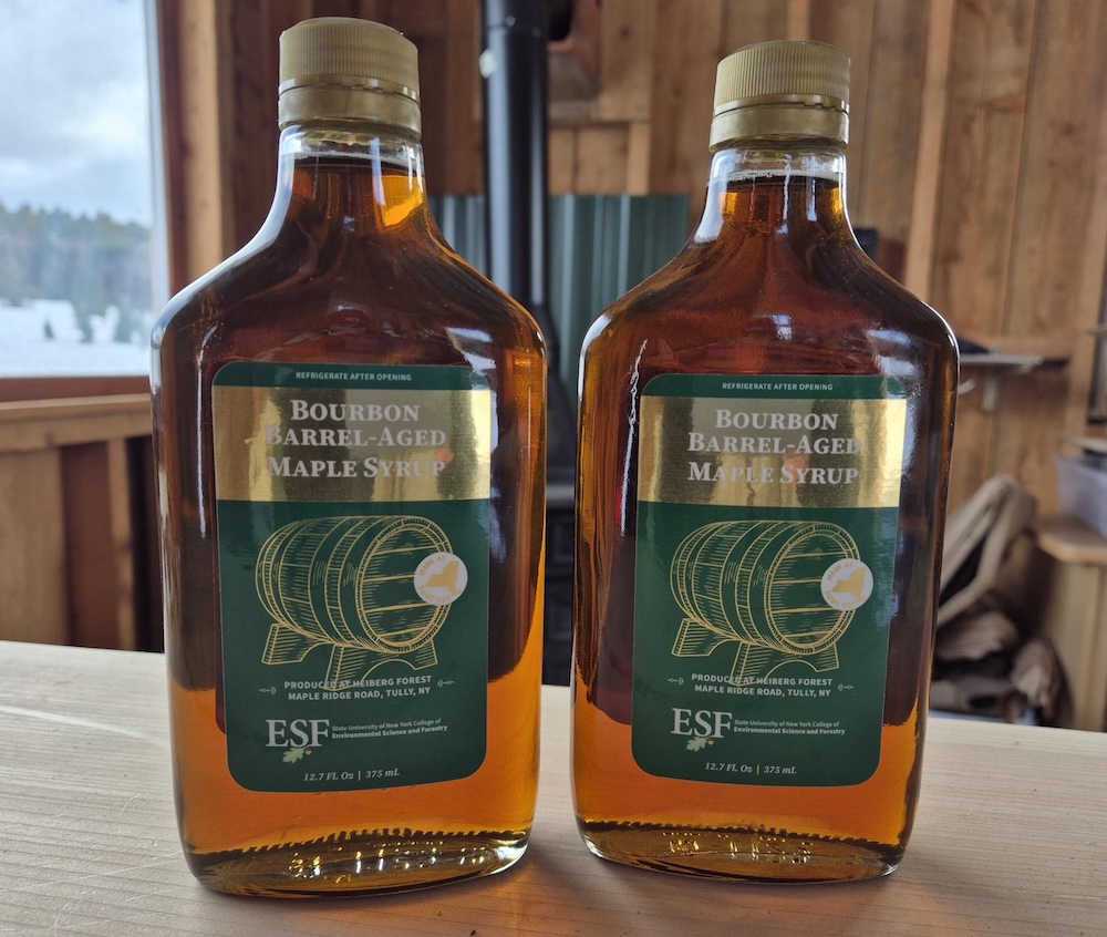 Two glass bottles of maple syrup with green labels.